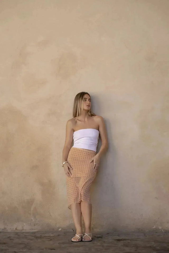 Femme portant une jupe midi imprimée beige et blanc, style élégant et tendance