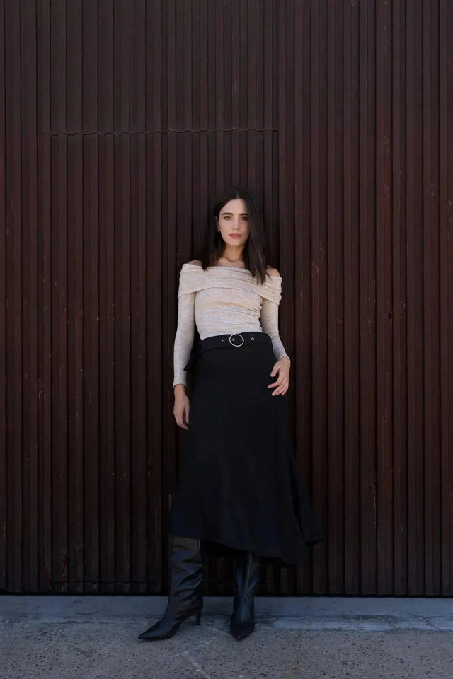 Femme portant la Jupe Midi Noire Avec Ceinture, affichant une silhouette flatteuse avec des bottes noires, parfaite pour une sortie élégante.