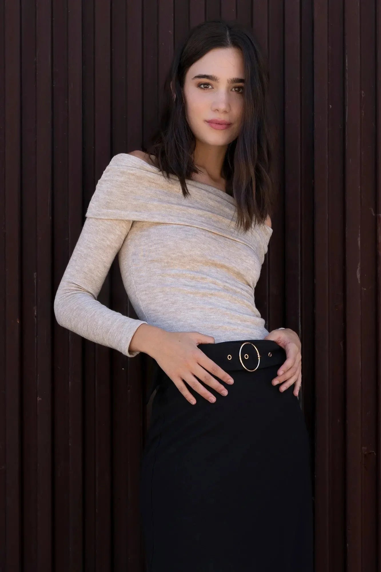 Femme portant une jupe midi noire avec ceinture et top crème, élégante et moderne