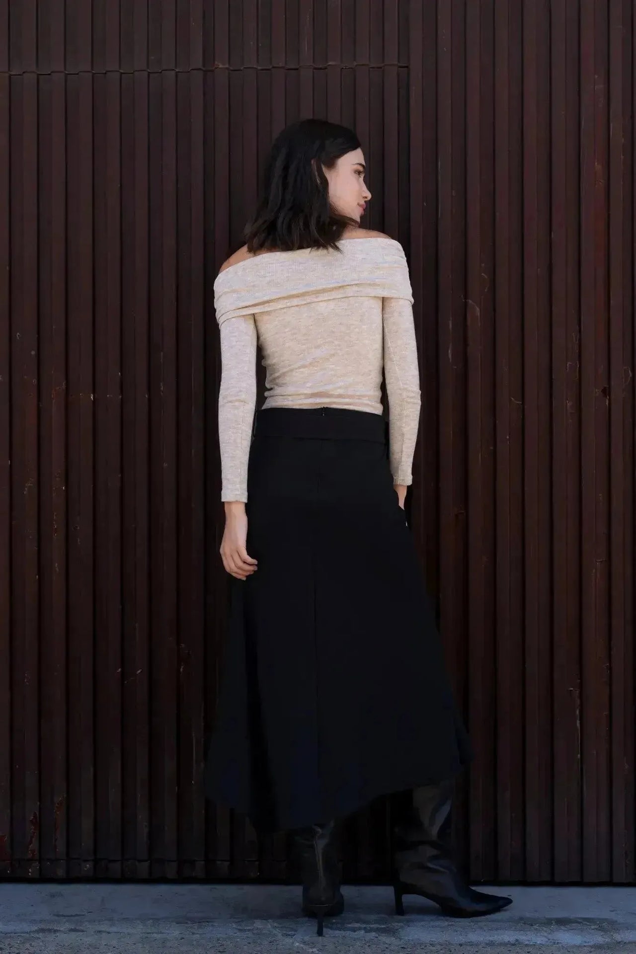 Femme de dos dans la Jupe Midi Noire Avec Ceinture, mettant en avant la coupe moderne et la taille haute, idéale pour toutes les silhouettes.