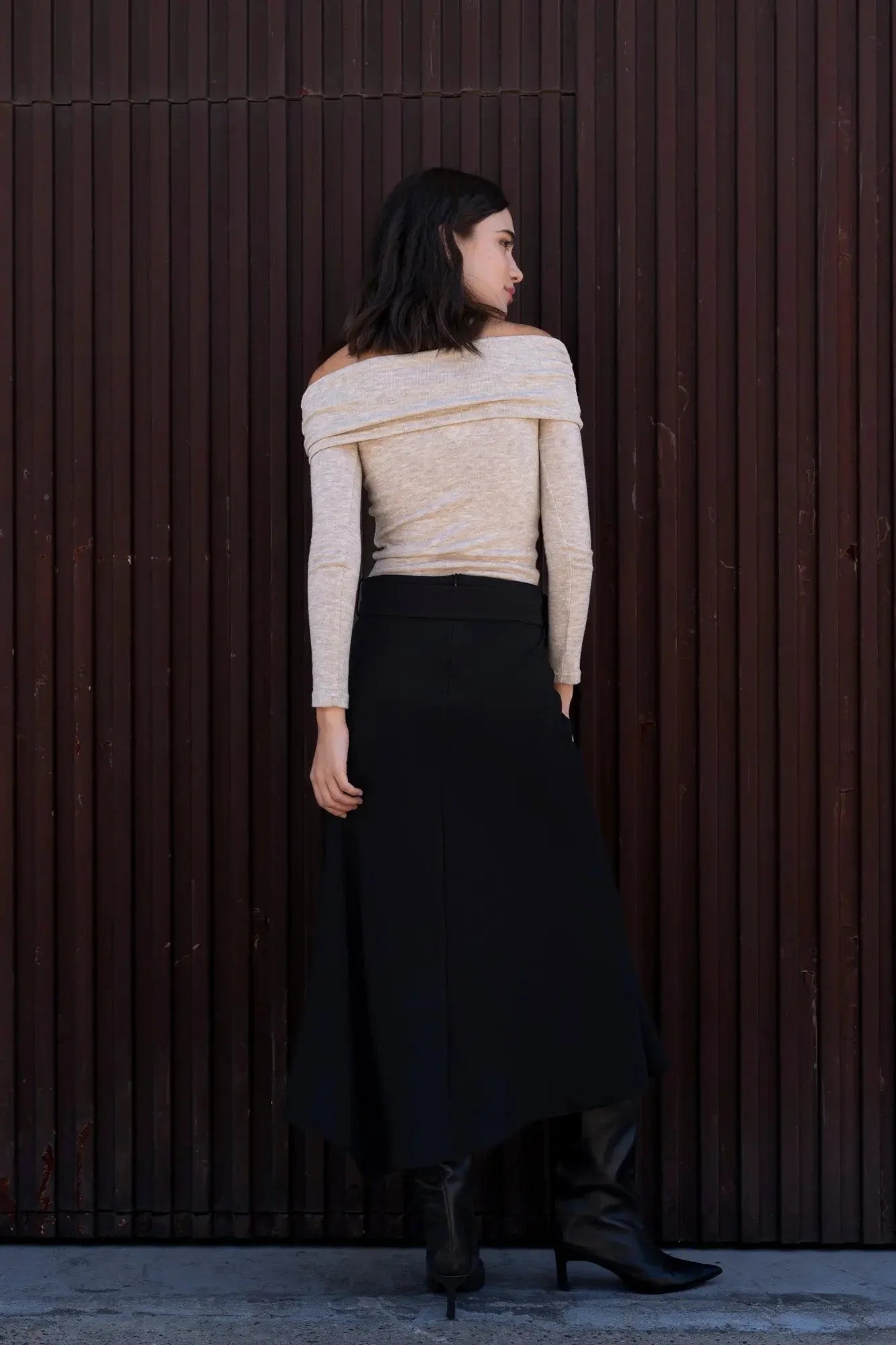 Jupe midi noire avec ceinture, top beige off-shoulder, bottines noires élégantes