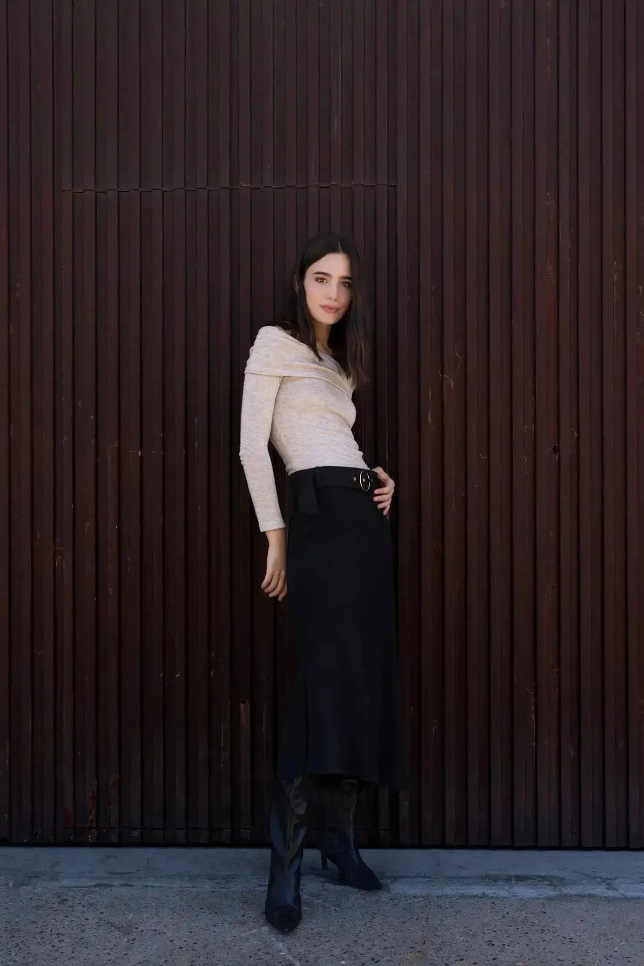 Femme posant avec confiance dans la Jupe Midi Noire Avec Ceinture, combinée avec un haut clair, idéale pour une tenue de jour chic.