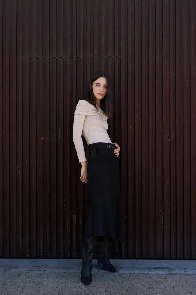 Femme posant avec confiance dans la Jupe Midi Noire Avec Ceinture, combinée avec un haut clair, idéale pour une tenue de jour chic.