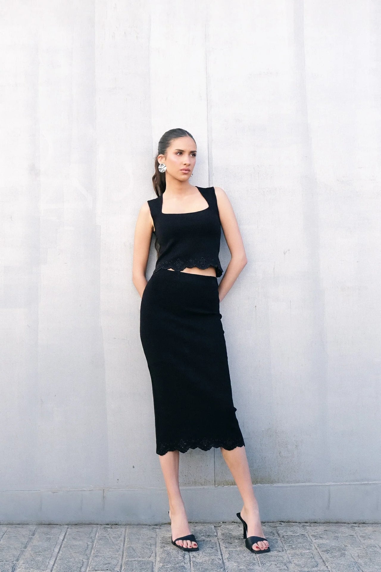 Modèle posant fièrement en jupe midi noire brodée, dégageant une élégance idéale pour une jupe chic et tendance.