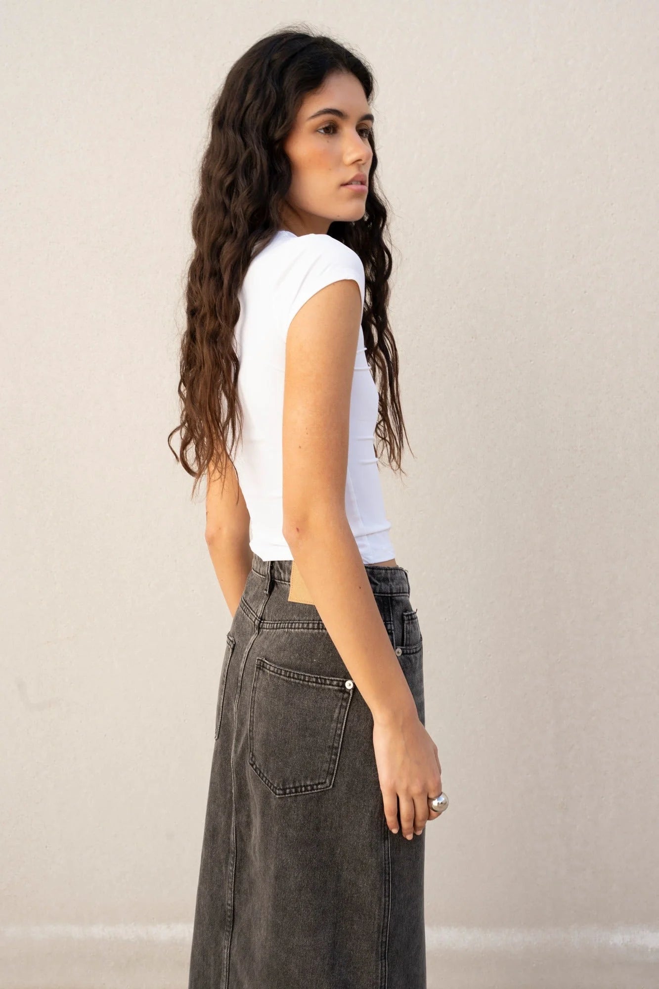 Femme portant une jupe midi en denim polyvalente avec fente et crop top blanc