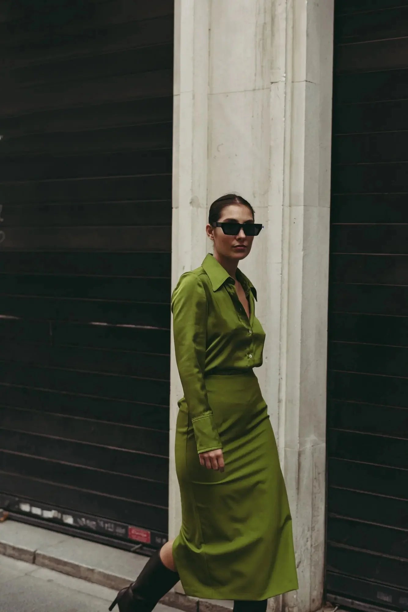 Femme en jupe verte longue élégante avec fente, posant dans la rue, illustrant un style urbain et chic.