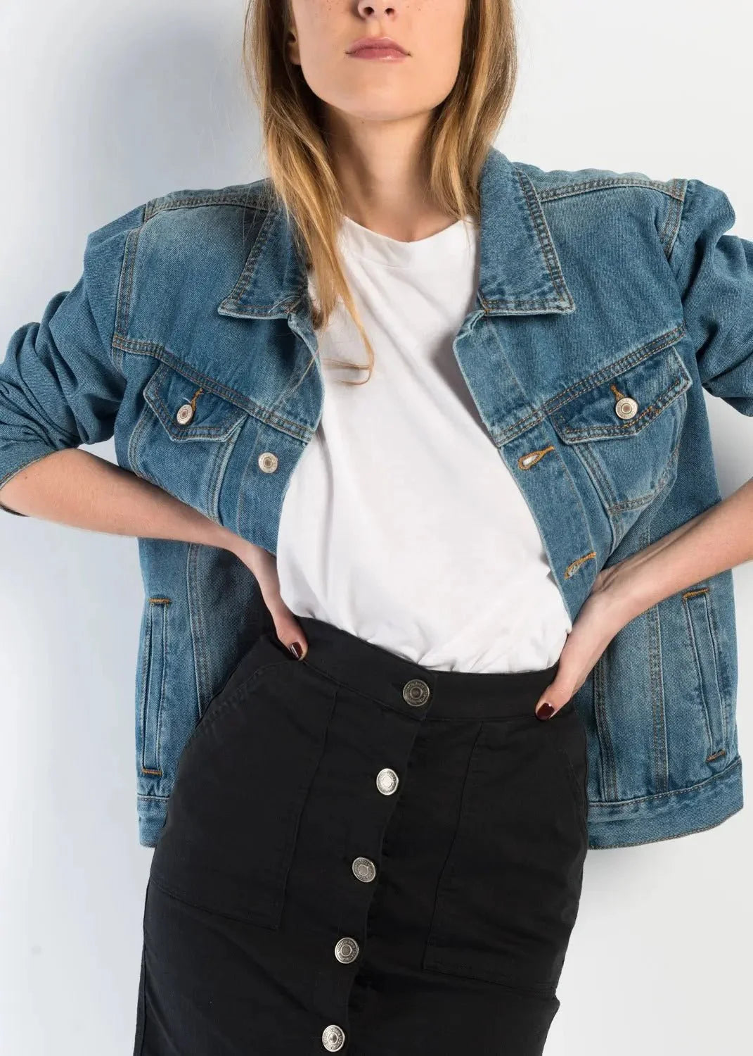Femme portant une jupe noire en denim, veste en jean bleu clair et t-shirt blanc