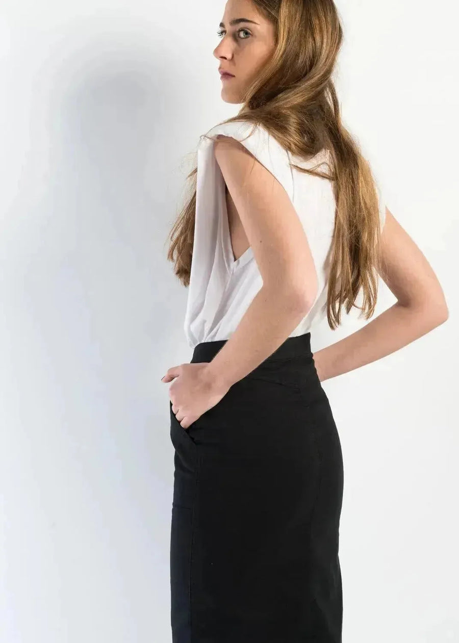 Femme porte une jupe bouton devant noire en denim mi-longue fendue, vue de dos, montrant le style chic et durable.