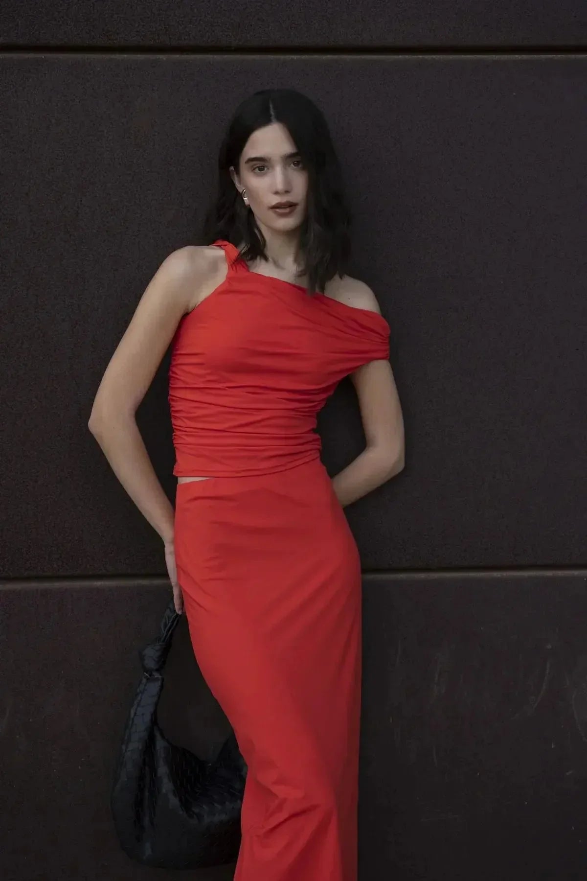 Femme en jupe rouge longue moulante taille basse en polyamide, posant de manière décontractée tout en mettant en valeur le style moderne.