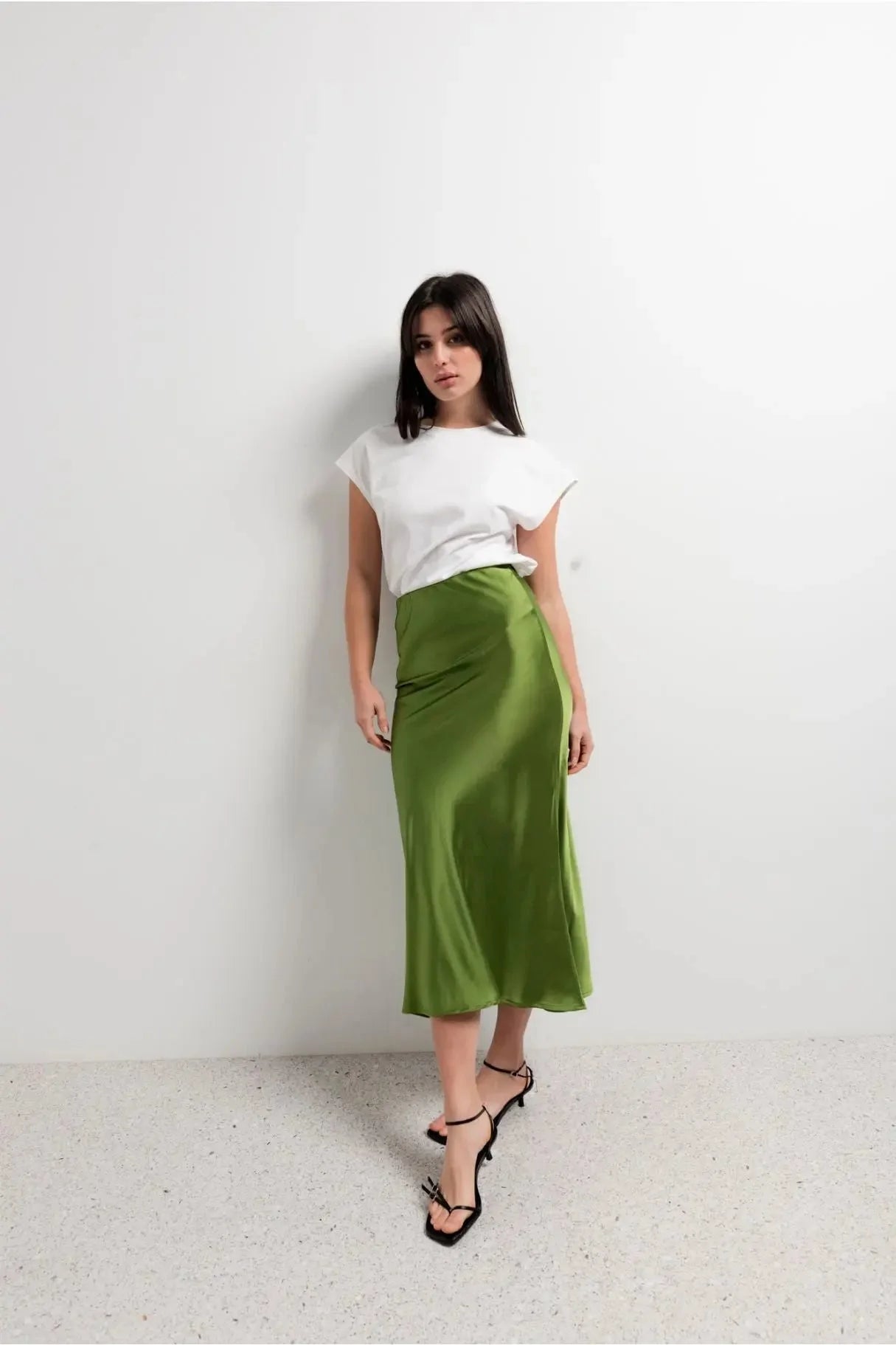 Modèle posant en jupe verte satin brillante avec un t-shirt blanc, idéale pour un style casual-chic.