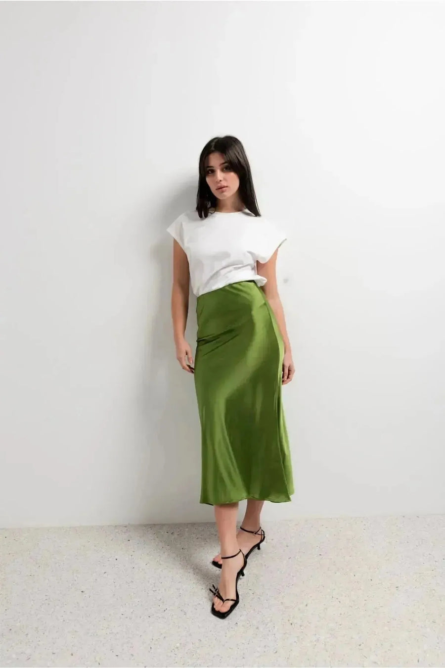 Modèle posant en jupe verte satin brillante avec un t-shirt blanc, idéale pour un style casual-chic.