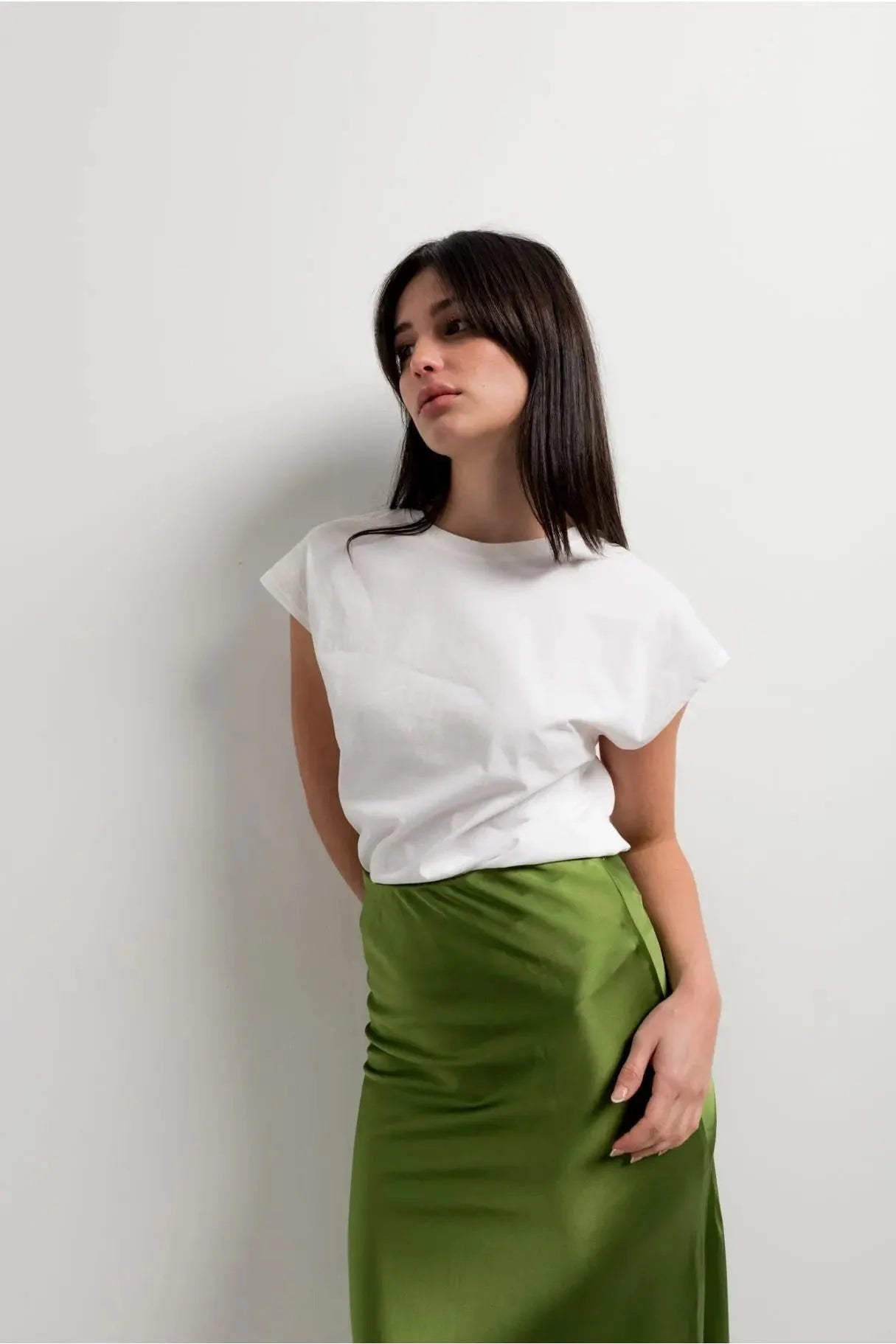 Femme portant une jupe verte satin élégante et confortable avec un haut blanc, parfaite pour toutes les occasions.