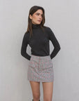 Femme portant une jupe-short à carreaux femme taille haute avec un col roulé noir, mettant en avant le style chic et confortable du skort.