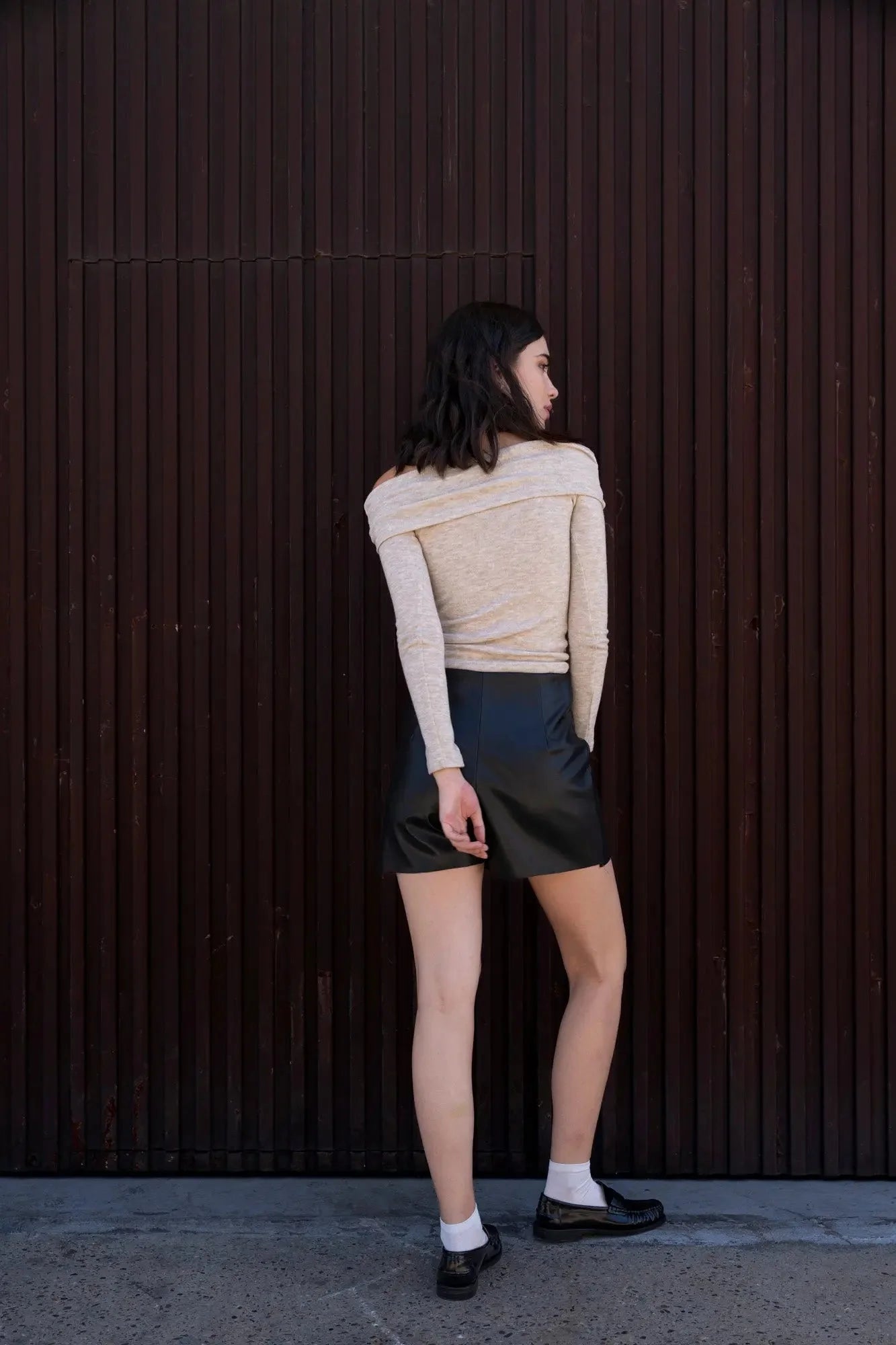 Femme portant une jupe short effet cuir avec top beige et loafers noirs