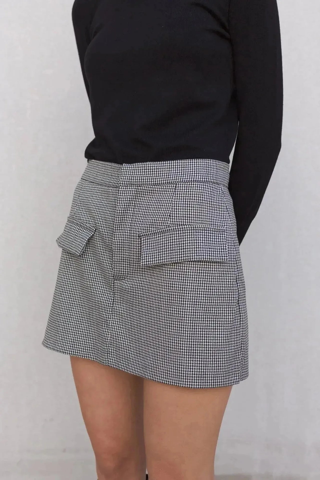 Zoom sur une jupe short mini à motifs portée avec un haut noir, montrant le design pratique des poches.