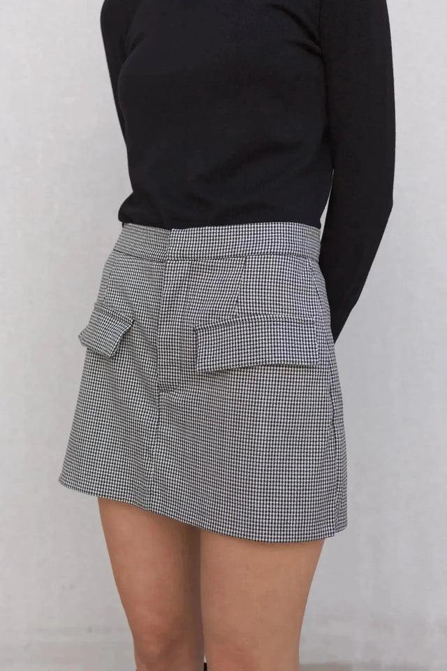 Zoom sur une jupe short mini à motifs portée avec un haut noir, montrant le design pratique des poches.
