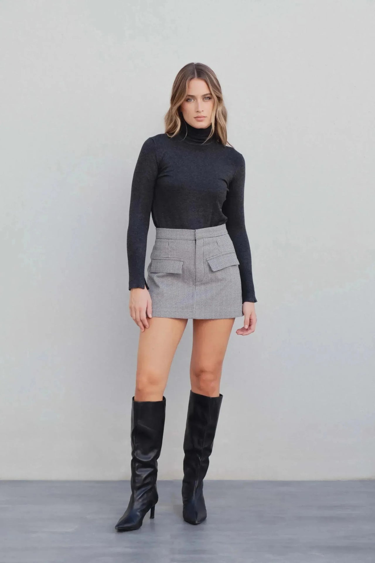 Modèle exposant un ensemble top noir et jupe short mini à motifs, accentuant le look chic et moderne.