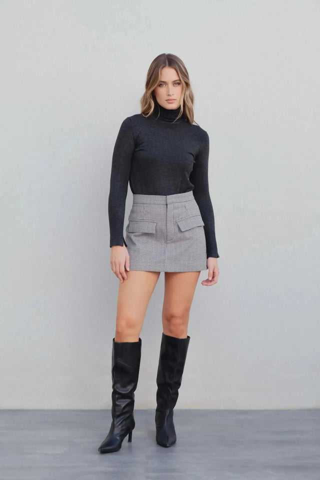 Modèle exposant un ensemble top noir et jupe short mini à motifs, accentuant le look chic et moderne.