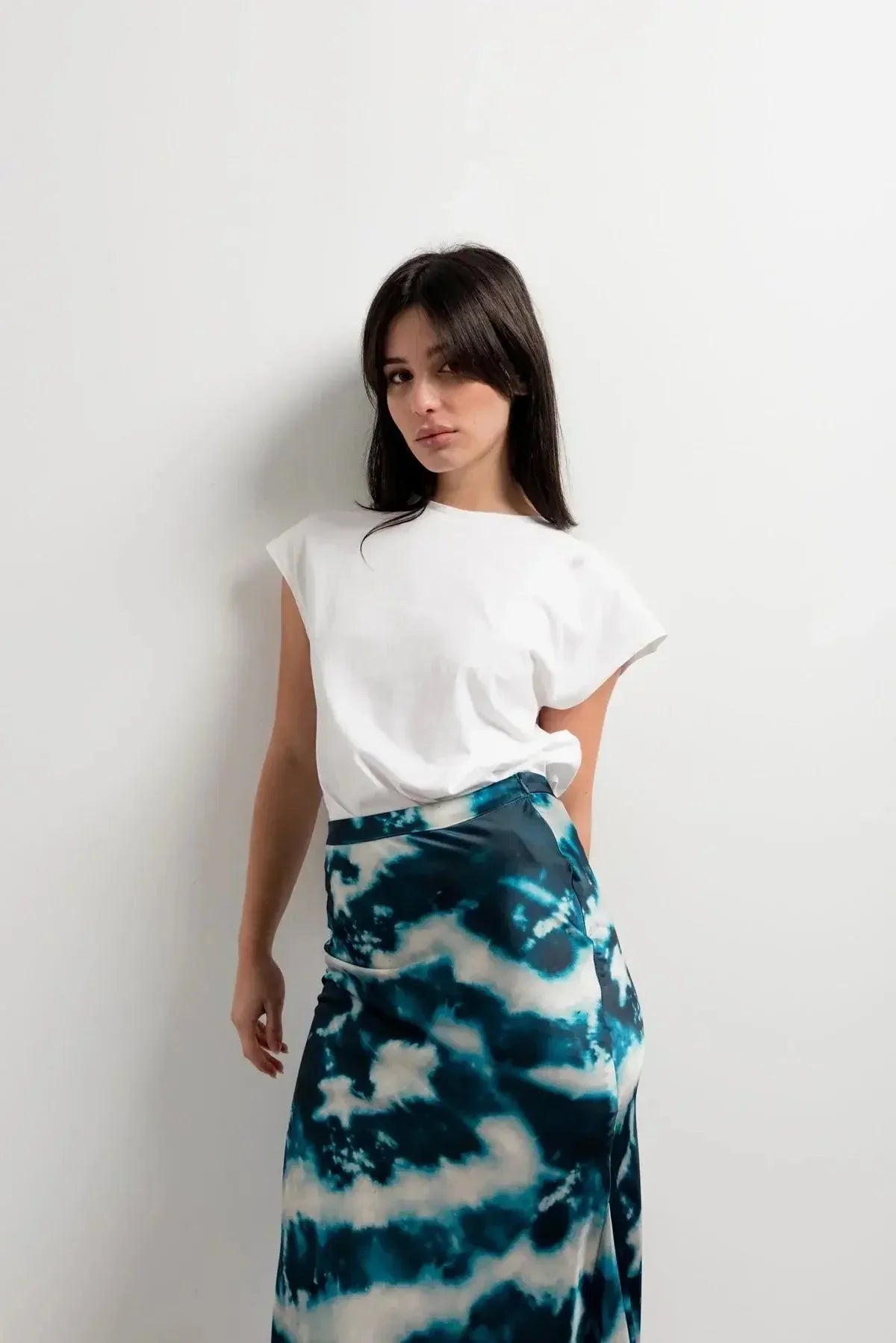 Femme posant en t-shirt blanc et jupe tie and dye satinée, démontrant l'élégance et la polyvalence de cette pièce incontournable.