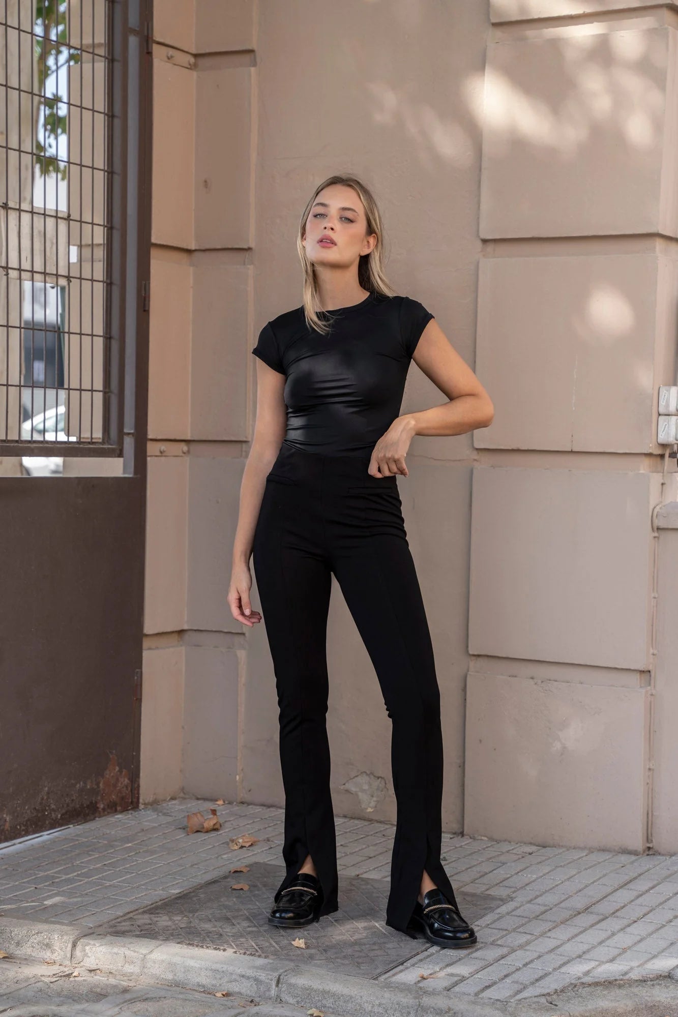 Femme portant leggings évasé noir à fentes avec top noir et loafers noirs