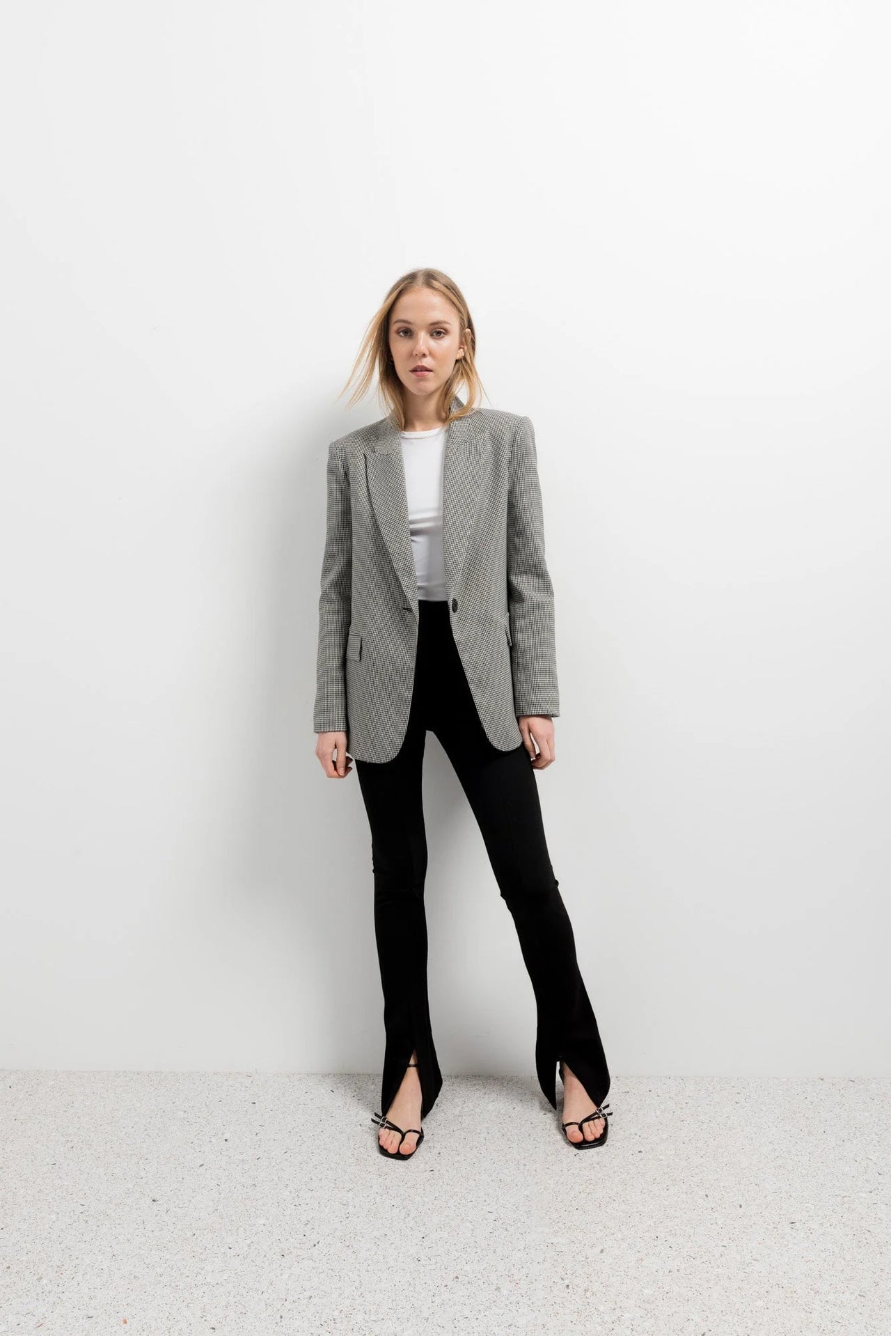 Femme habillée chic avec un blazer sur des leggings évasé noir à fentes, parfaite pour une sortie professionnelle.