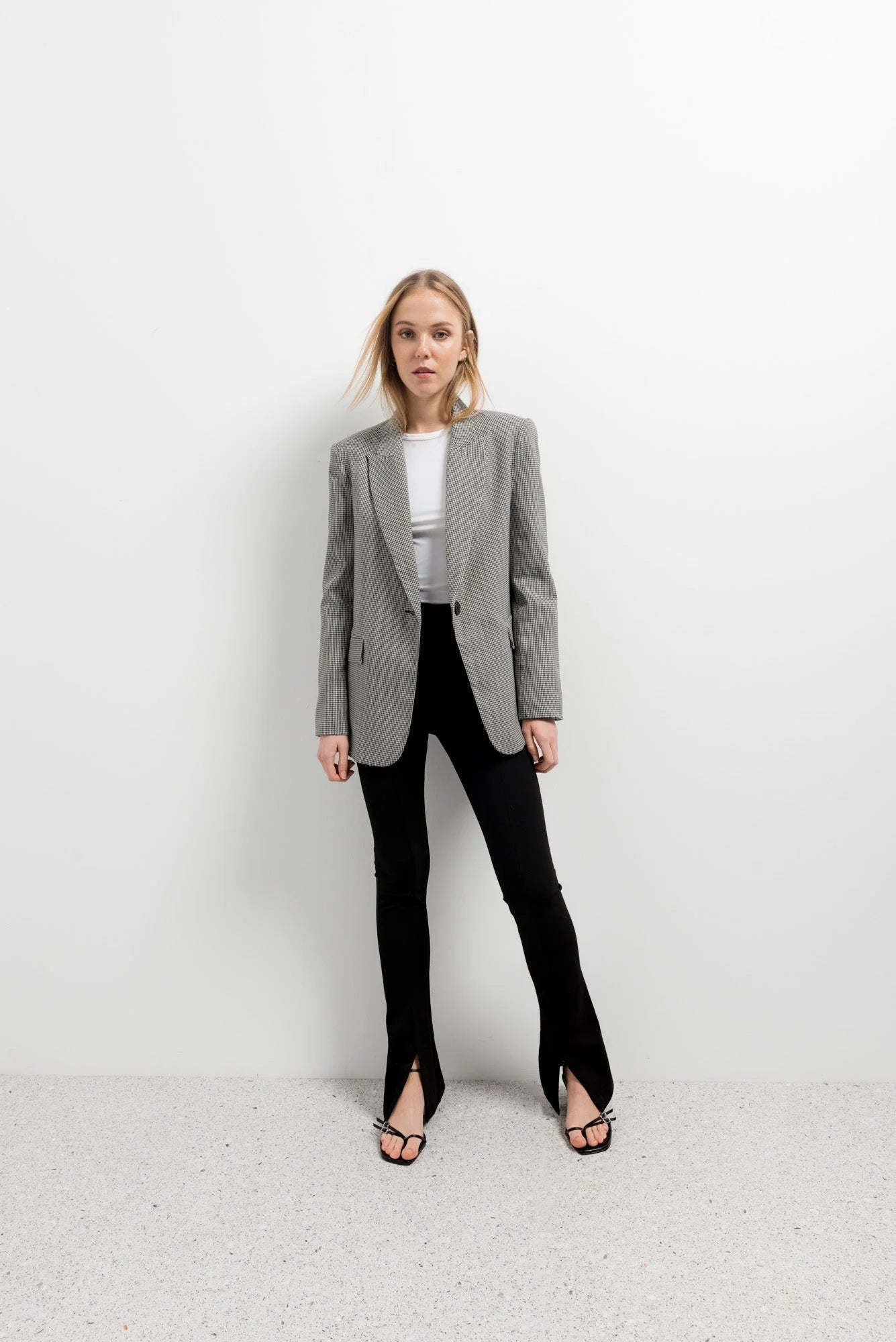Femme portant leggings évasé noir à fentes, blazer gris, crop top blanc et heels