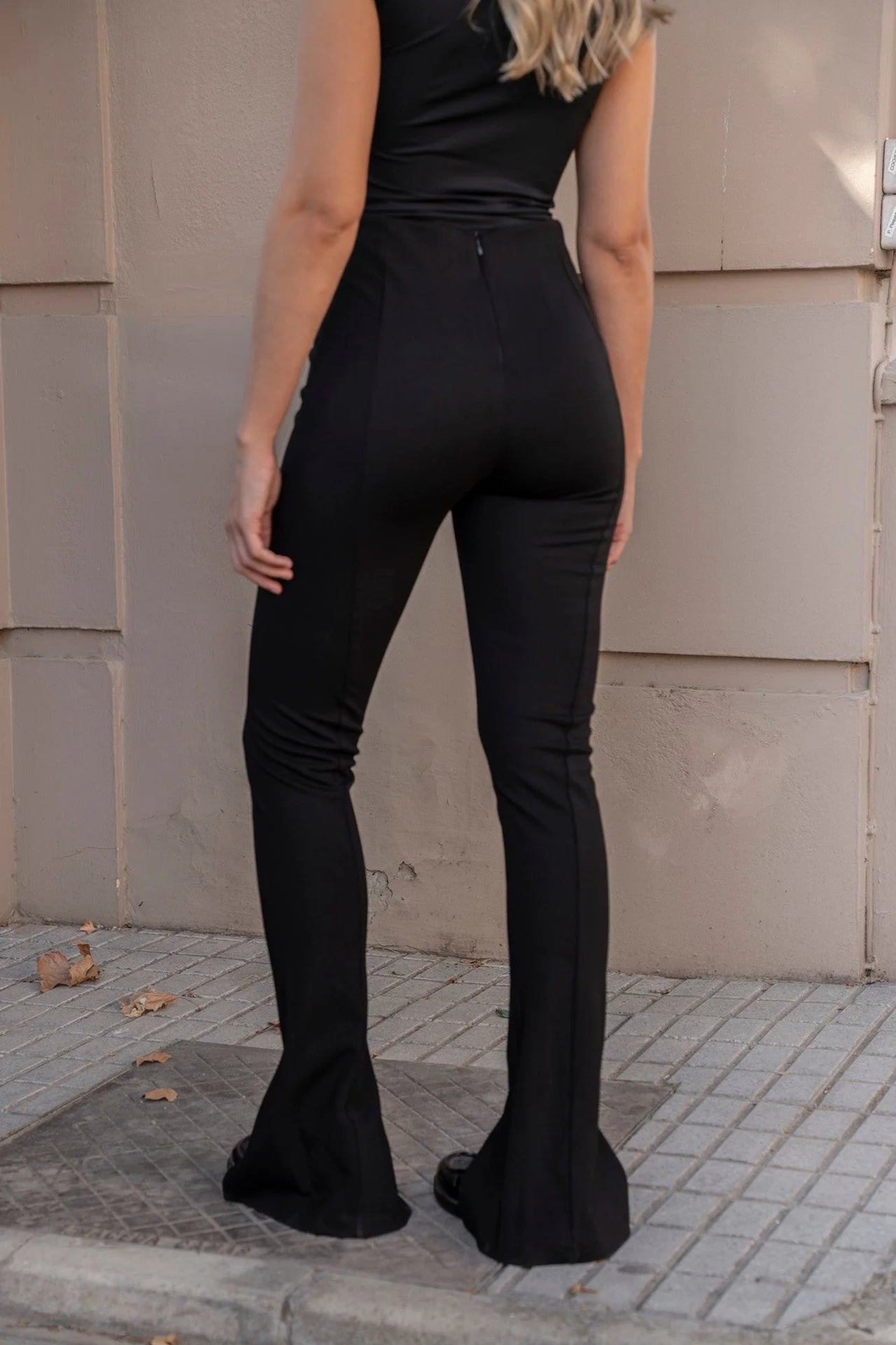 Vue arrière d'une femme en leggings évasé noir à fentes, mettant en avant la coupe flatteuse.