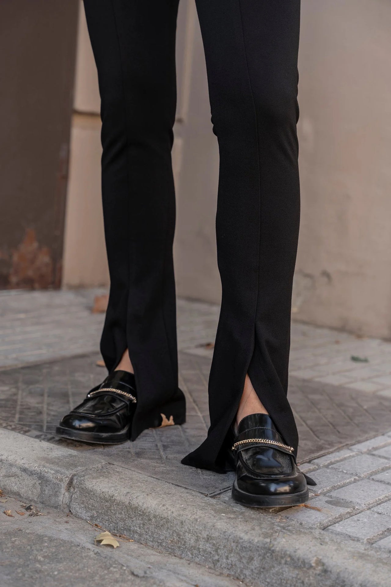 Détail sur les jambes d'une femme en leggings évasé noir à fentes, montrant les chaussures et la coupe évasée.