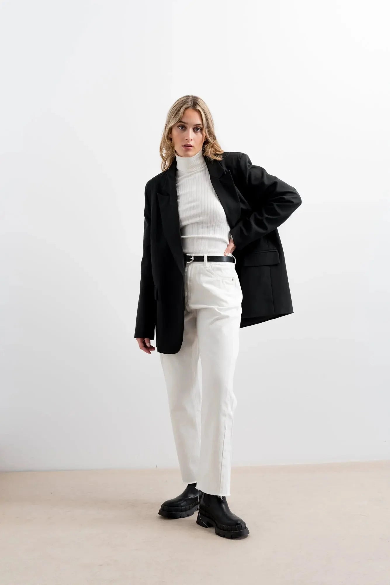 Femme en blazer noir turtleneck blanc et pantalon blanc pour la garde-robe d’hiver