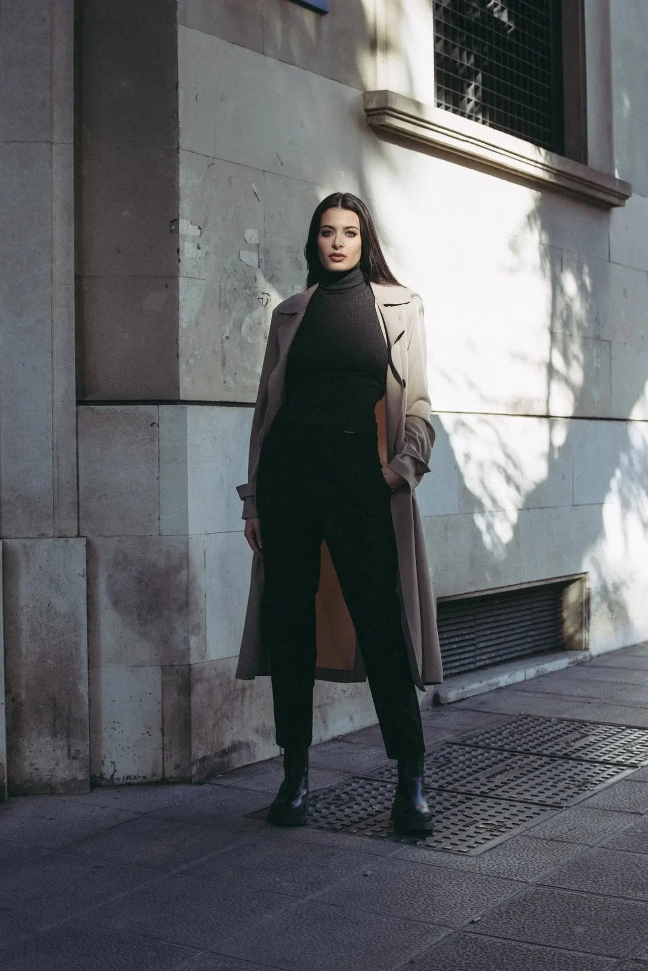 Femme élégante en pull col roulé femme sous un trench beige, une tenue idéale faisant partie des indispensables de la garde-robe d’hiver.