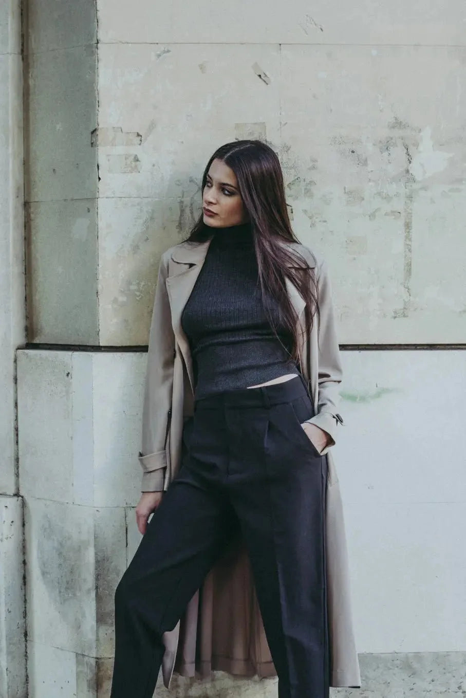 Femme en garde-robe d’hiver avec turtleneck noir, pantalon noir et trench beige