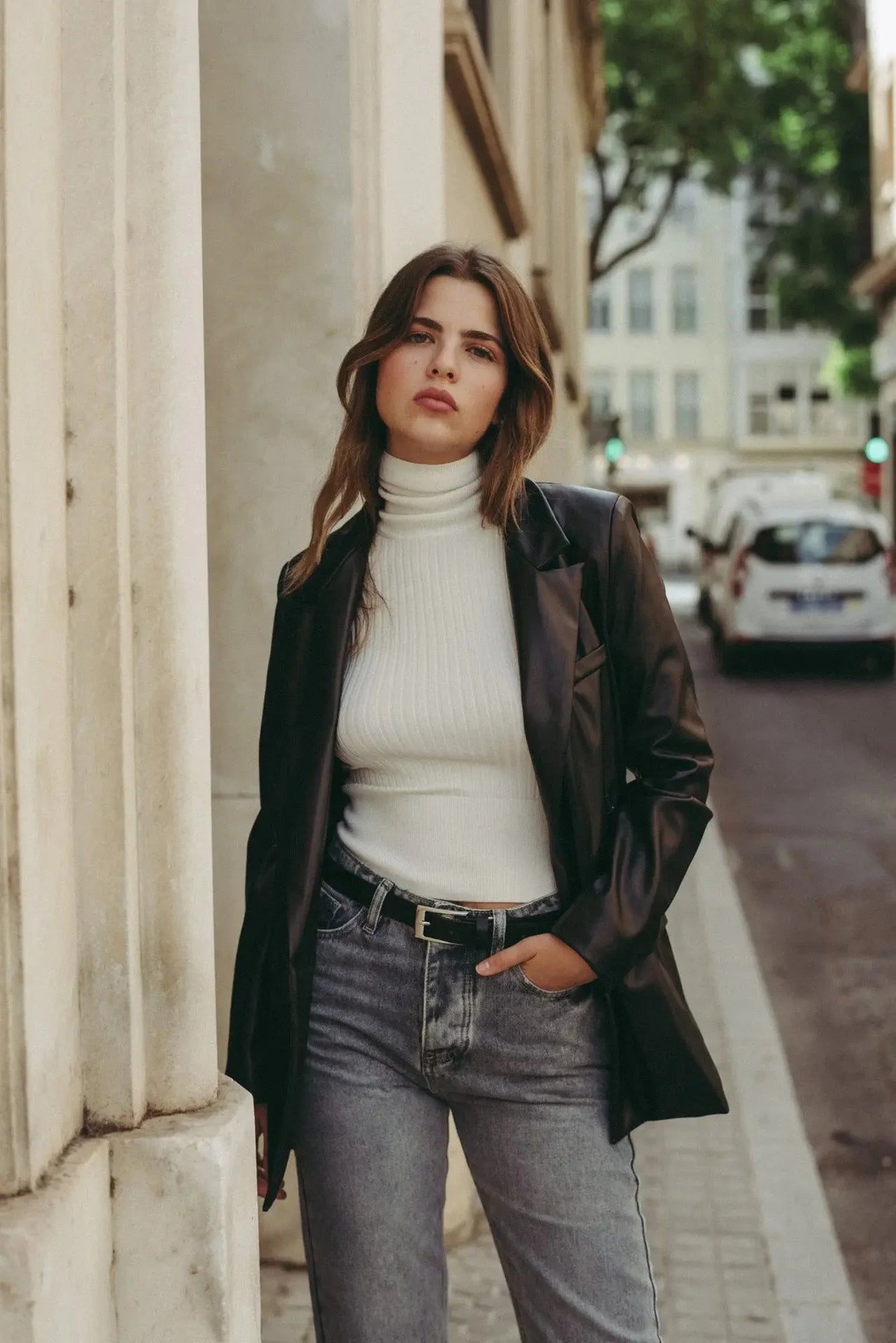 Femme en pull col roulé femme blanc, associée à un blazer noir et des jeans, un look parfait des indispensables de la garde-robe d’hiver.