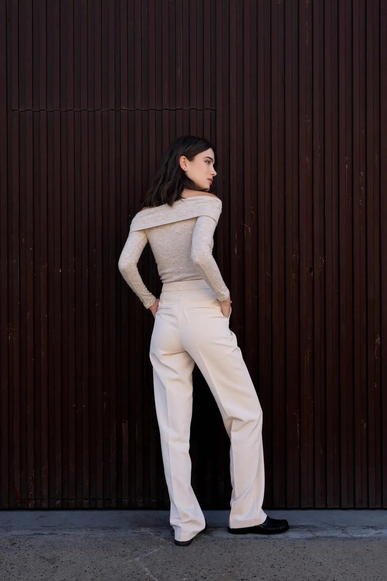 Vue arrière d'une femme dans un pantalon droit femme beige, soulignant la coupe ajustée et le design sophistiqué.