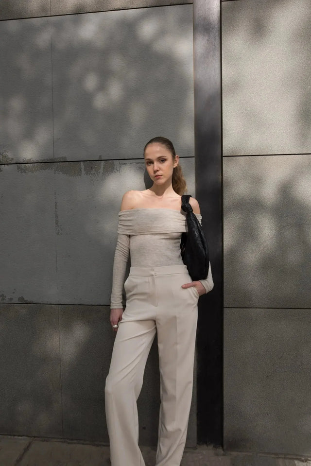 Femme portant un pantalon droit femme beige, affichant un look minimaliste avec une touche de chic en milieu urbain.