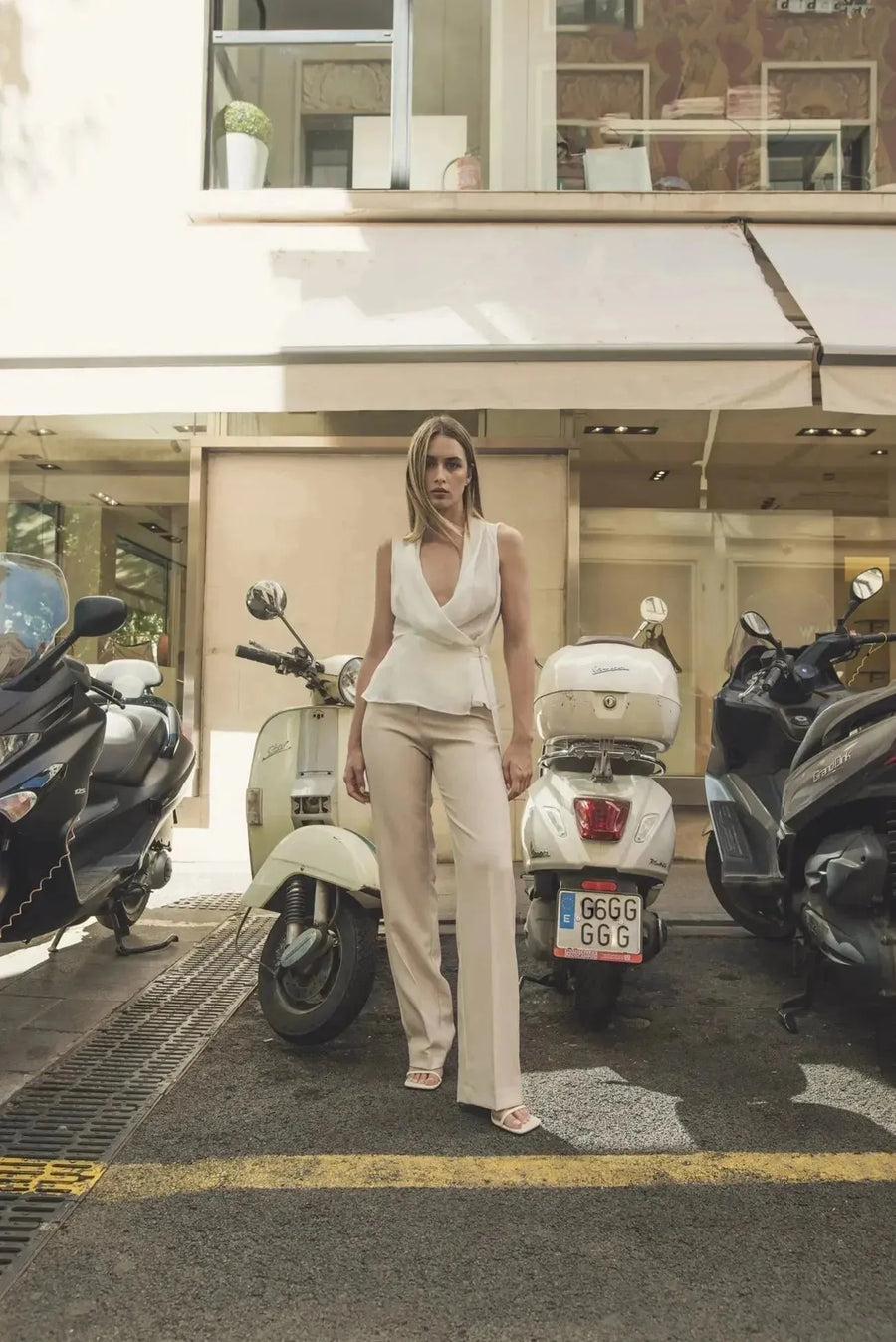Femme en pantalon droit femme beige, se tenant devant une scène urbaine, combinant élégance et décontraction.
