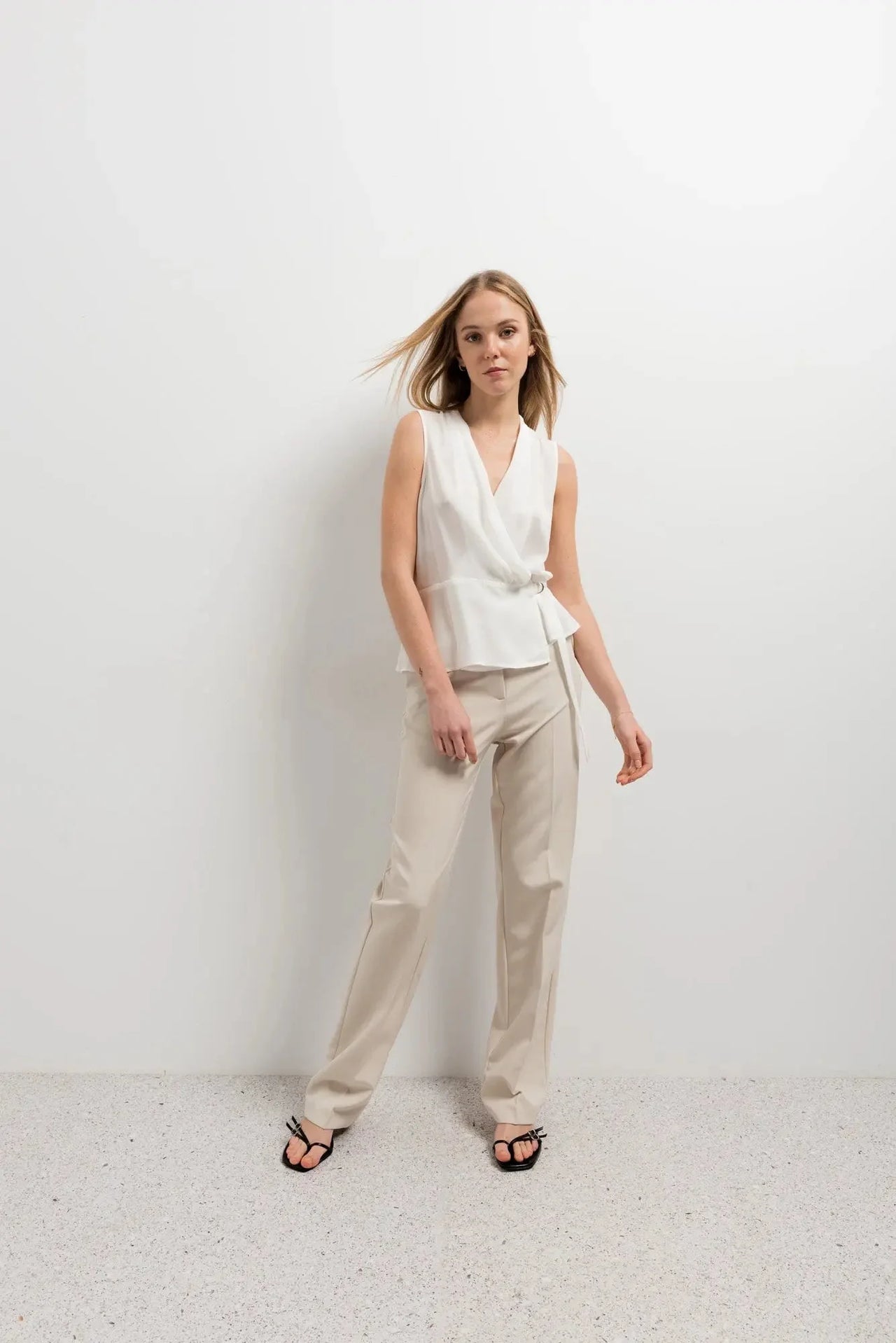 Femme en pantalon droit femme beige, mettant en avant un look sophistiqué avec un haut blanc, parfait pour diverses occasions.