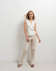 Femme en pantalon droit femme beige, mettant en avant un look sophistiqué avec un haut blanc, parfait pour diverses occasions.