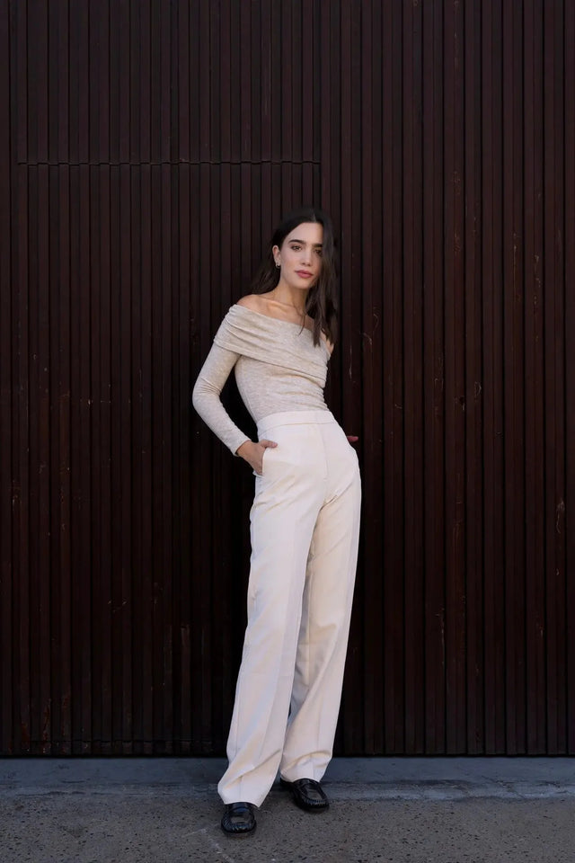 Modèle en pantalon droit femme beige, stylisé avec un haut à épaules dénudées, illustrant le confort et l'élégance intemporelle.