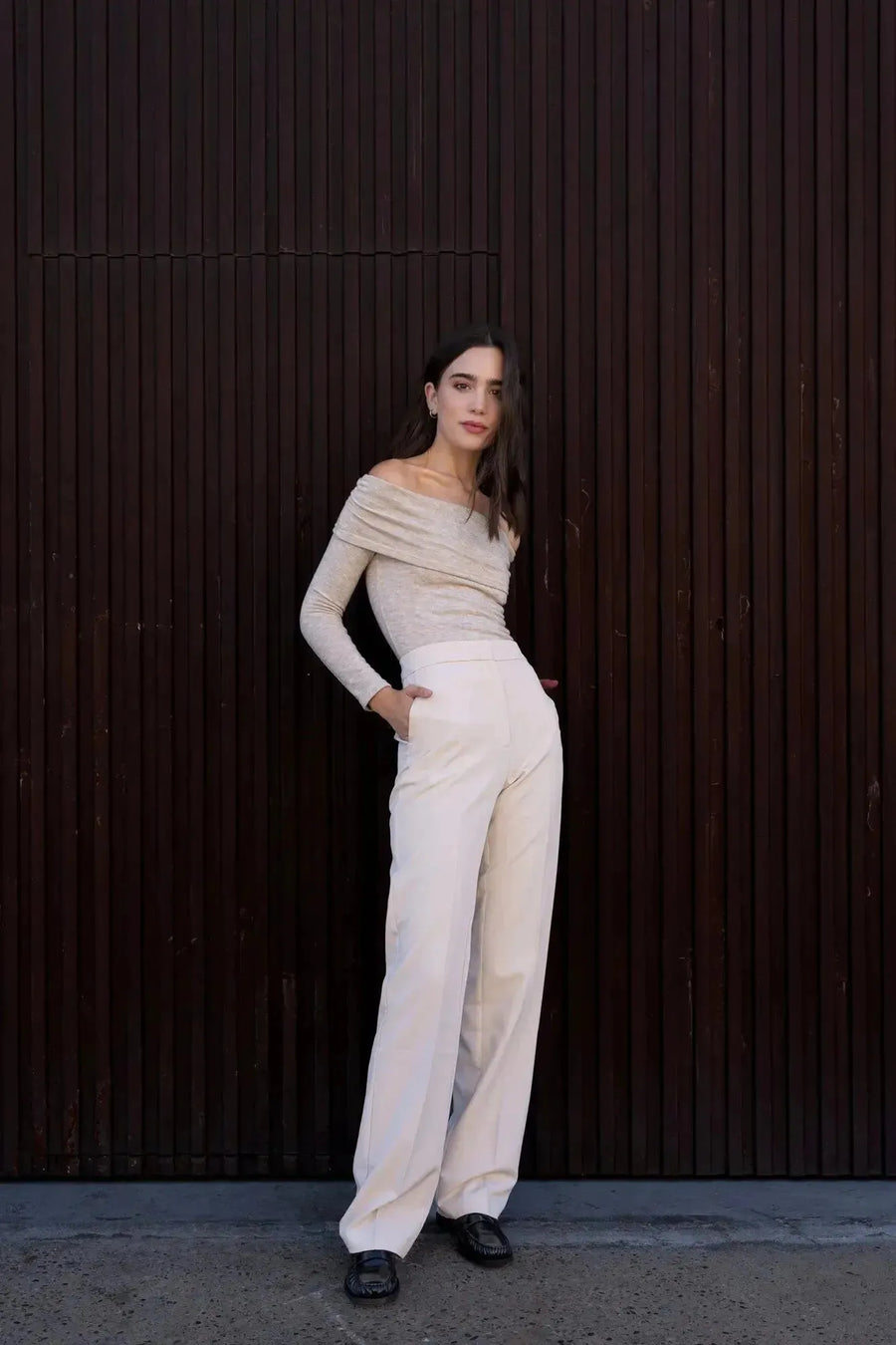 Modèle en pantalon droit femme beige, stylisé avec un haut à épaules dénudées, illustrant le confort et l'élégance intemporelle.