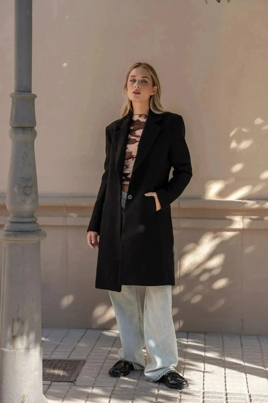 Manteau ajusté en laine pour femme, en pose décontractée dans un cadre extérieur, idéal pour un look hivernal. Manteau femme chic hiver.