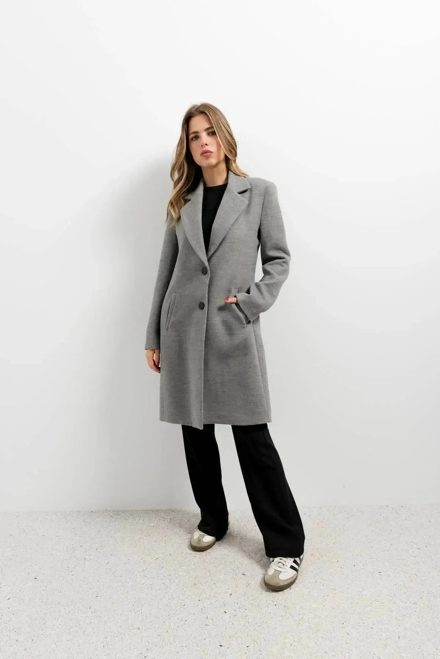Manteau ajusté en laine pour femme, coloris gris, porté avec un pantalon noir pour un look moderne. Manteau femme chic hiver.