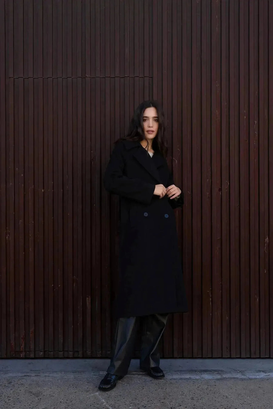 Femme captivante dans un manteau long chaud femme noir à double boutonnage, affichant un look sophistiqué et décontracté.