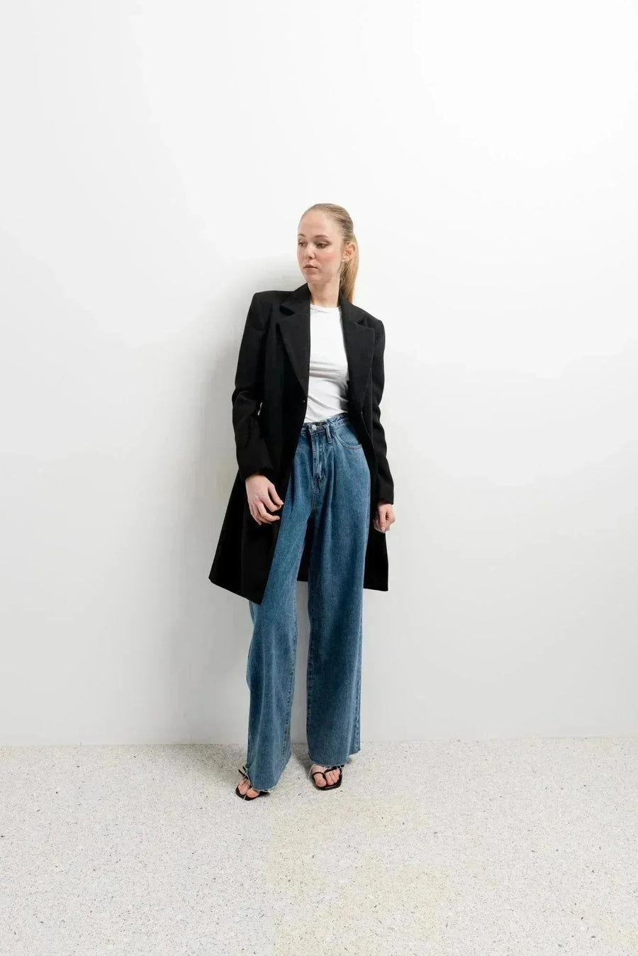 Femme dans un manteau long chaud femme noir à double boutonnage, associée à un jean large, créant un look tendance et décontracté.