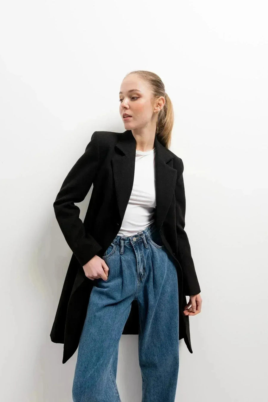 Femme portant un manteau long chaud femme noir à double boutonnage, élégant avec un style décontracté, parfaite pour l'hiver.