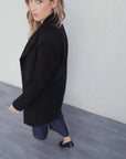 Femme portant un manteau col en noir avec blazer et pantalons bleus foncés