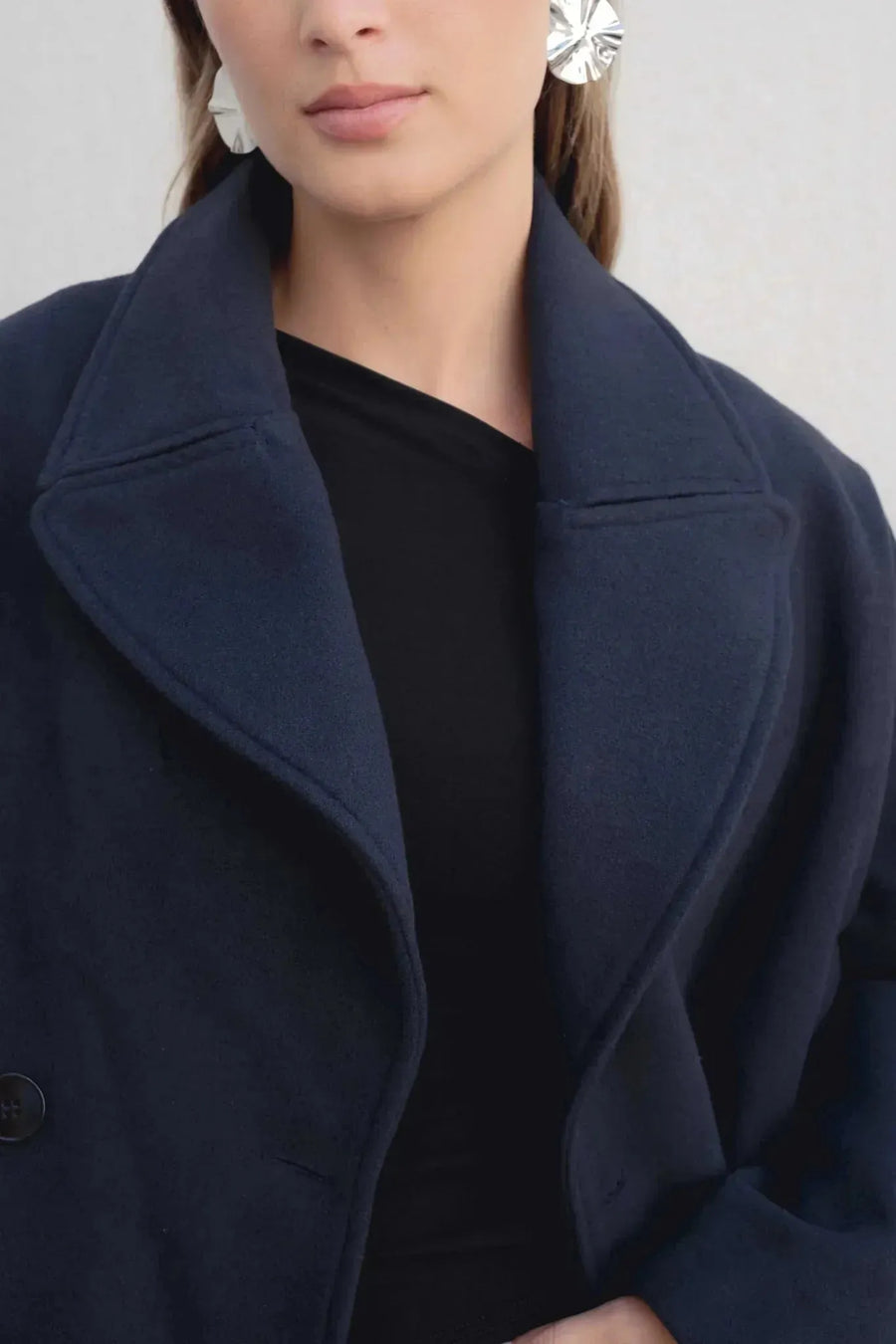 Détail du col revers du manteau court bleu marine femme, avec un accent sur le style chic et ample.
