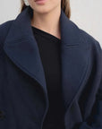 Détail du col revers du manteau court bleu marine femme, avec un accent sur le style chic et ample.
