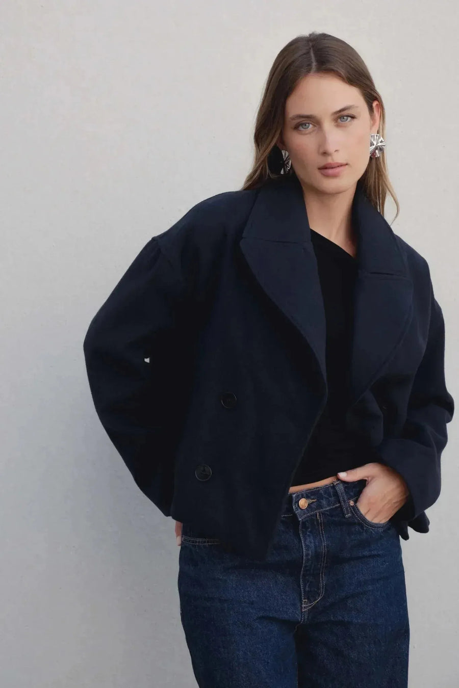 Manteau court bleu marine femme aperçu de près, mettant en valeur les boutons et le col revers large.