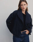 Manteau court bleu marine femme aperçu de près, mettant en valeur les boutons et le col revers large.