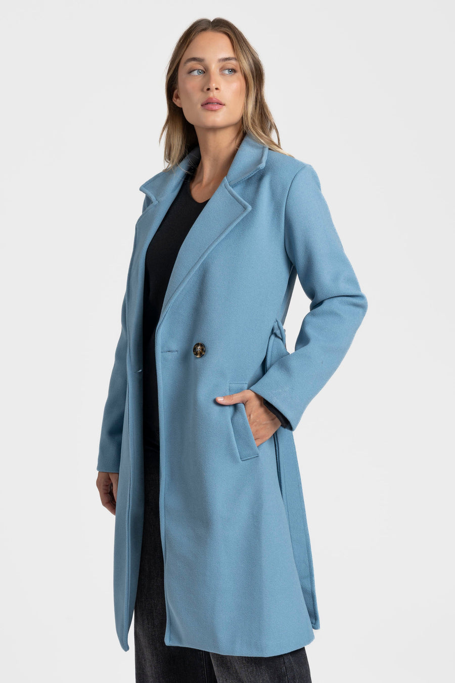 Manteau bleu clair ouvert vu de trois quarts, main dans la poche latérale